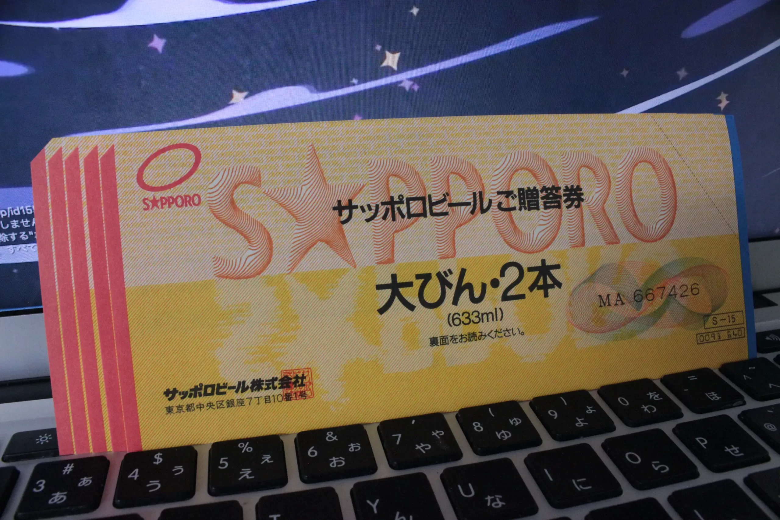 サッポロビールご贈答券（大びん2本・633ml）がパソコンのキーボード上に置かれている様子